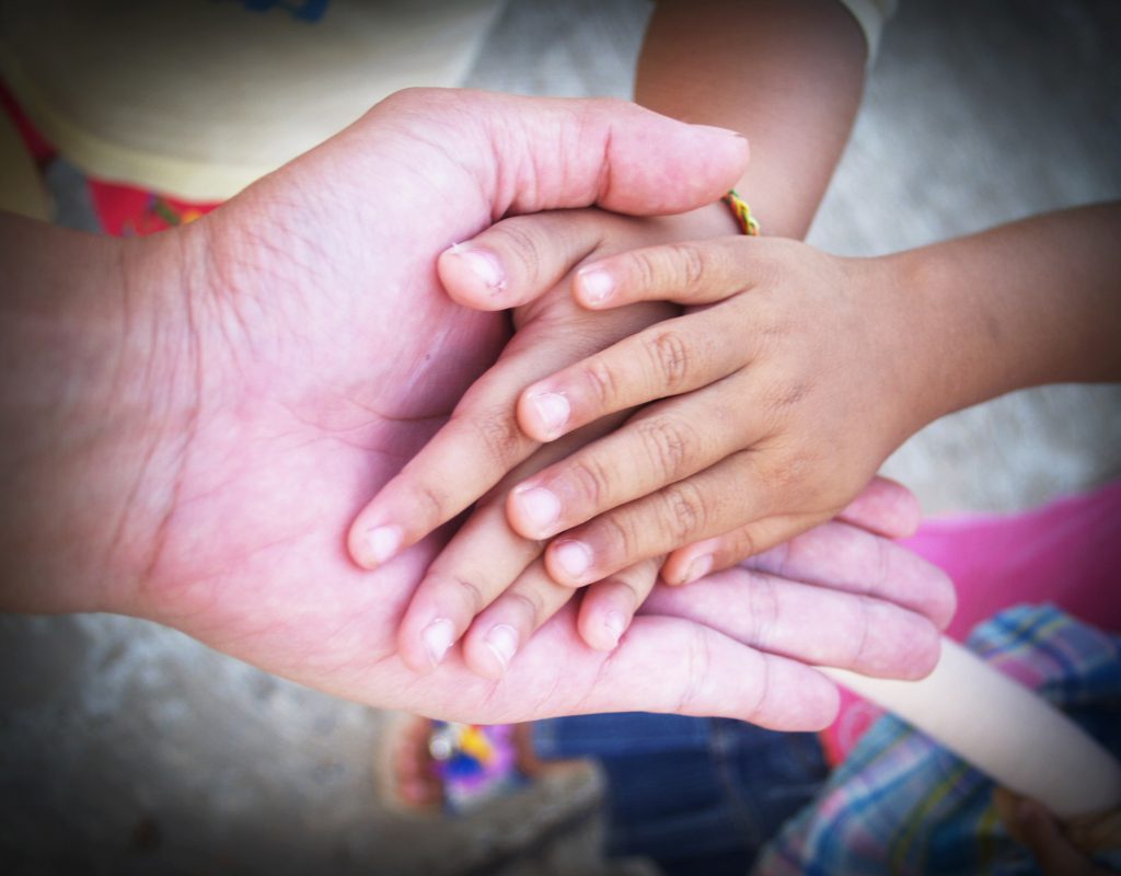 adult hand holding 2 kid's hands